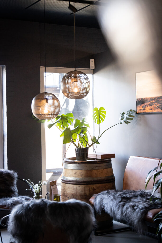 Hyggelig lounge hos Wine & Delights Blåvand med vinfat, pærenetræ og varme pendellamper
